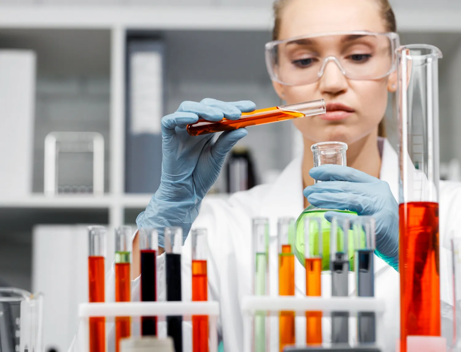 Scienziata con provette colorate in laboratorio, analisi di laboratorio