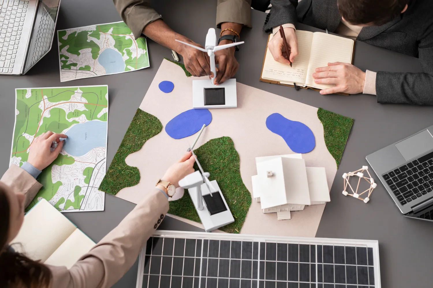 Team di consulenti ambientali con mappe e modelli di energia rinnovabile